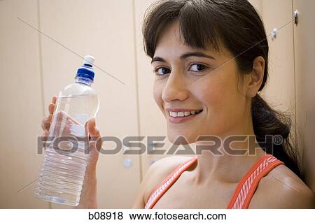 Portrait of a young woman holding a water bottle View Large Photo Image Stock Photo - Portrait of a young woman holding a water bottle. Fotosearch
