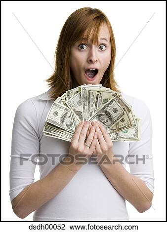 Stock Image - Portrait of a young woman holding fanned out dollar bills. Fotosearch