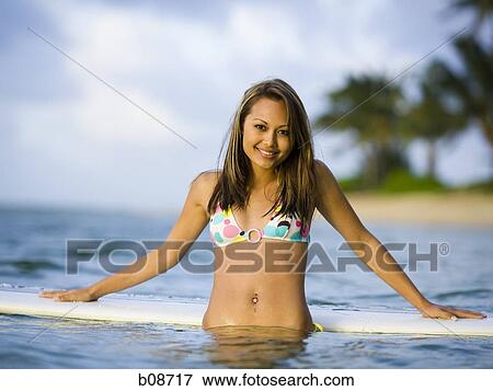 Stock Photo - Portrait of a young woman leaning against a surfboard. Fotosearch