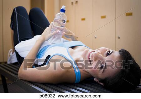 Portrait of a young woman lying on a bench holding a water bottle View Large Photo Image Stock Image - Portrait of a young woman lying on a bench holding a water bottle. Fotosearch