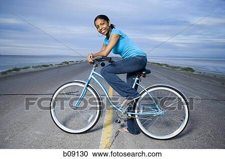 Portrait of a young woman sitting on a bicycle View Large Photo Image Stock Image - Portrait of a young woman sitting on a bicycle. Fotosearch