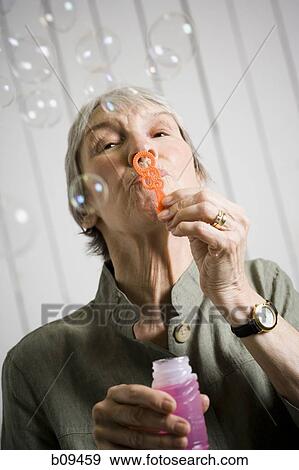 Portrait of an elderly woman blowing bubbles with a bubble wand View Large Photo Image Stock Photo - Portrait of an elderly woman blowing bubbles with a bubble wand. Fotosearch