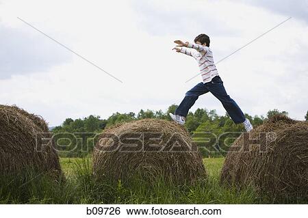 Profile of a boy leaping on hay bales View Large Photo Image Stock Photograph - Profile of a boy leaping on hay bales. Fotosearch