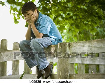 Profile of a boy with his hands on his face sitting on a wooden fence View Large Photo Image Stock Photography - Profile of a boy with his hands on his face sitting on a wooden fence. Fotosearch