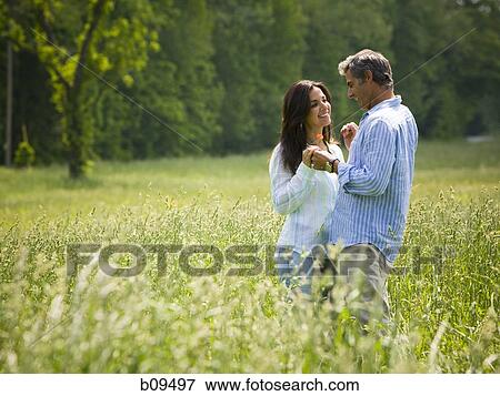 Stock Photo - Profile of a man and a woman holding hands in a field. Fotosearch