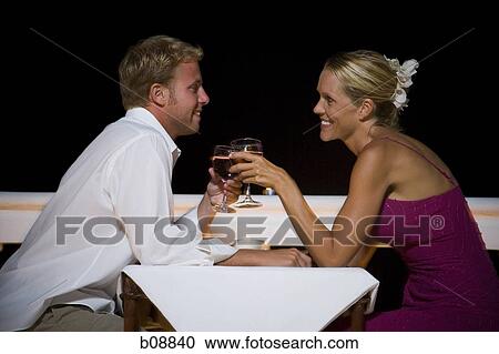 Stock Image - Profile of a man and a woman toasting with wineglasses. Fotosearch