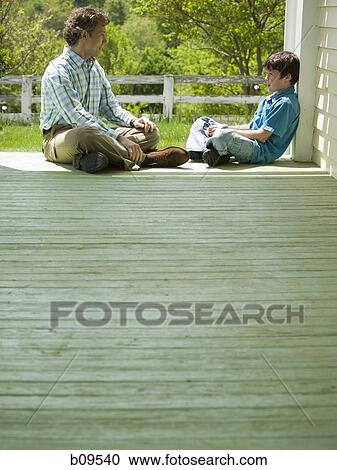 Stock Image - Profile of a man and his son sitting on a wooden floor. Fotosearch