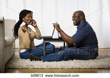 Profile of a mature woman talking on a mobile phone with a man sitting in front of her View Large Photo Image Stock Image - Profile of a mature woman talking on a mobile phone with a man sitting in front of her. Fotosearch