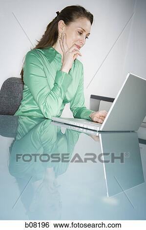Stock Photograph - Profile of a woman using a laptop. Fotosearch