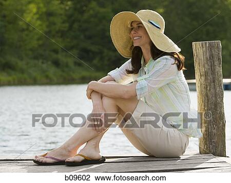 Profile of a woman wearing a straw hat and sitting on a pier View Large Photo Image Stock Image - Profile of a woman wearing a straw hat and sitting on a pier. Fotosearch