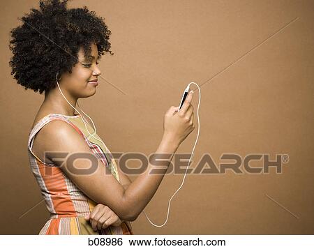 Stock Photograph - Profile of a young woman listening to an MP3 player. Fotosearch