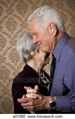 Stock Image - Profile of an elderly couple dancing and listening to music. Fotosearch