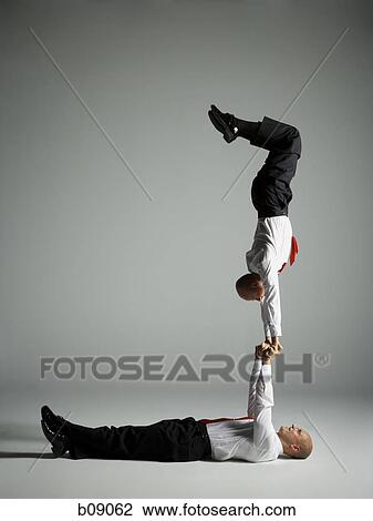Stock Image - Profile of two male acrobats in business suits performing. Fotosearch