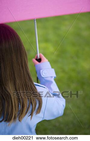 Rear view of a girl holding an umbrella View Large Photo Image Stock Image - Rear view of a girl holding an umbrella. Fotosearch