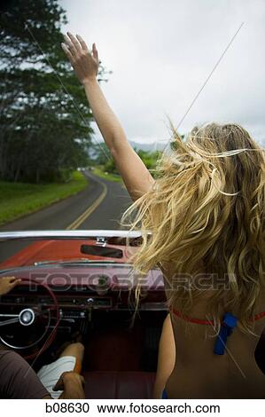 Rear view of a young woman sitting in a car with her hand raised View Large Photo Image Stock Image - Rear view of a young woman sitting in a car with her hand raised. Fotosearch