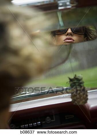 Reflection of a young woman in the rear view mirror of a car View Large Photo Image Stock Photo - Reflection of a young woman in the rear view mirror of a car. Fotosearch
