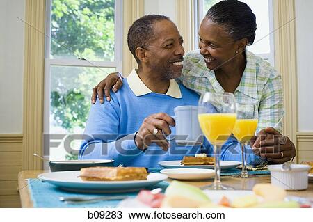 Stock Image - Senior man and a senior woman smiling at the breakfast table. Fotosearch