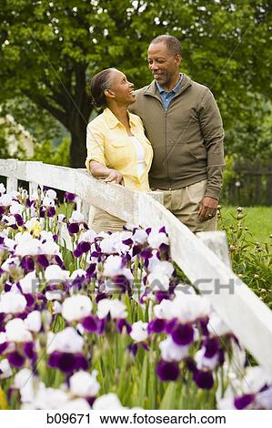 Stock Image - Senior man and a senior woman standing near a fence. Fotosearch