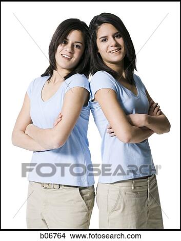 Sisters back to back with arms crossed View Large Photo Image Picture - Sisters back to back with arms crossed. Fotosearch