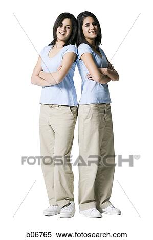 Stock Photography - Sisters back to back with arms crossed. Fotosearch