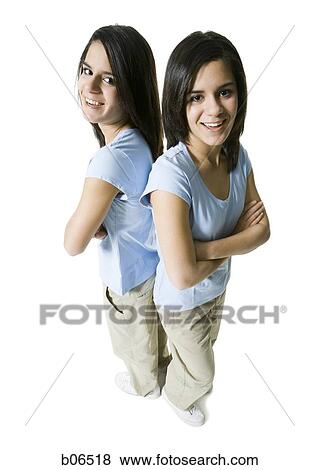 Sisters standing back to back with arms crossed View Large Photo Image Stock Photo - Sisters standing back to back with arms crossed. Fotosearch