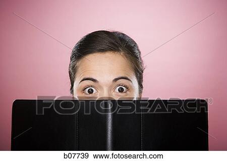 Stock Photo - Startled woman peeking over a binder. Fotosearch
