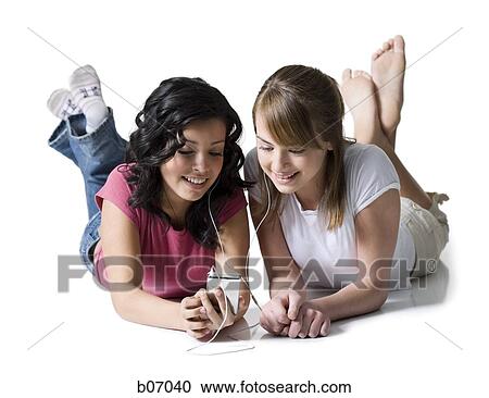 Teenage friends lying down with listening device View Large Photo Image Stock Image - Teenage friends lying down with listening device. Fotosearch