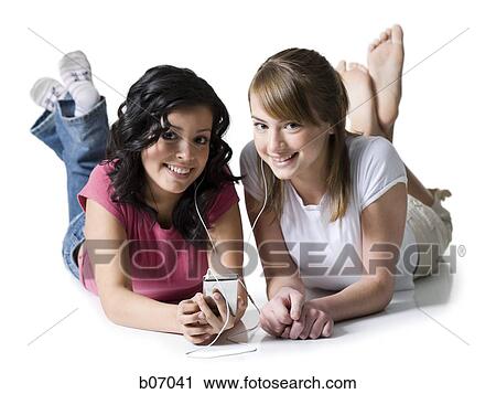 Teenage friends lying down with listening device View Large Photo Image Stock Image - Teenage friends lying down with listening device. Fotosearch