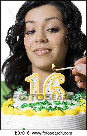 Stock Photograph - Teenage girl lighting birthday candle. Fotosearch