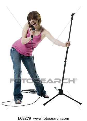 Teenage girl singing into a microphone View Large Photo Image Stock Photo - Teenage girl singing into a microphone. Fotosearch