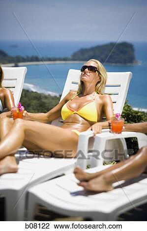 Three women relaxing on deck loungers View Large Photo Image Stock Image - Three women relaxing on deck loungers. Fotosearch