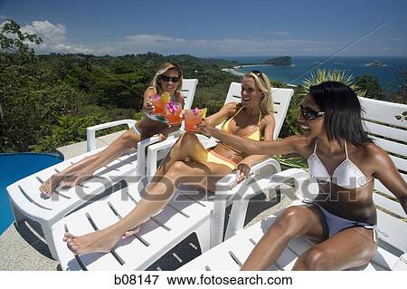 Stock Photo - Three women relaxing on deck loungers. Fotosearch