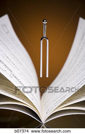 Tuning fork hovering over musical score View Large Photo Image Picture - Tuning fork hovering over musical score. Fotosearch