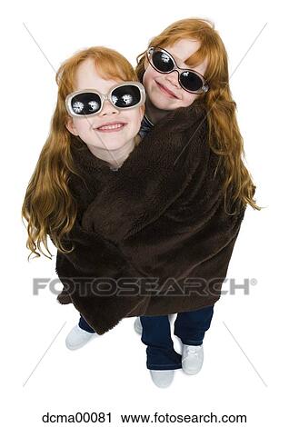 Stock Image - Twin sisters with sunglasses wrapped in blanket. Fotosearch