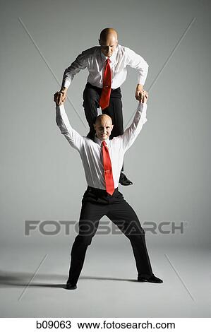 Stock Image - Two male acrobats in business suits performing. Fotosearch