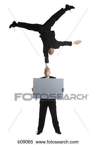 Stock Photography - Two male acrobats in business suits performing. Fotosearch