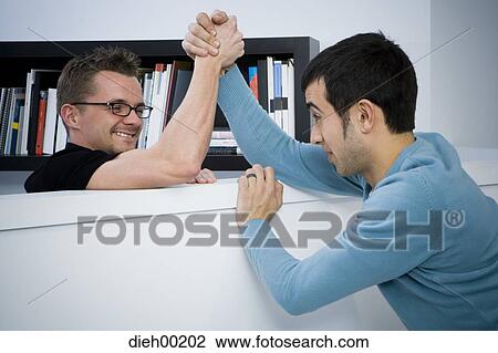 Stock Image - Two male office employees playing and arm wrestling. Fotosearch