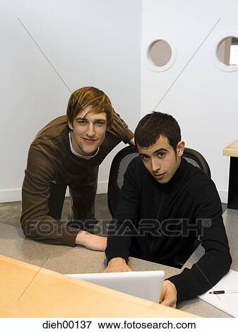 Stock Photo - Two male office workers with laptop. Fotosearch
