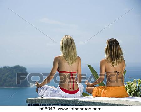 Two women performing yoga exercises by infinity pool View Large Photo Image Stock Image - Two women performing yoga exercises by infinity pool. Fotosearch