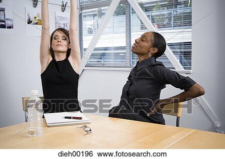 Two women stretching at table View Large Photo Image Stock Photograph - Two women stretching at table. Fotosearch