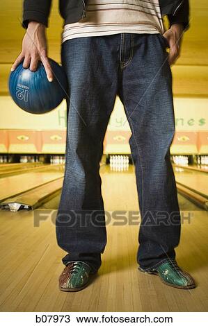 Stock Image - Waist down shot of male bowler holding a bowling ball. Fotosearch
