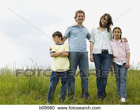 Stock Image - woman and a man standing with their son and daughter in a field. Fotosearch