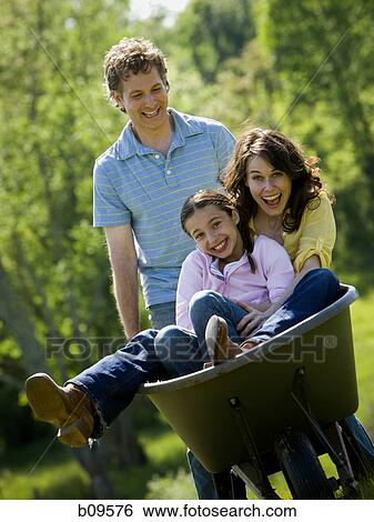 woman and her daughter sitting in a wheel barrow with a man standing beside them View Large Photo Image Stock Photograph - woman and her daughter sitting in a wheel barrow with a man standing beside them. Fotosearch