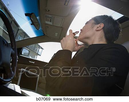 Woman applying lipstick in car View Large Photo Image Stock Photo - Woman applying lipstick in car. Fotosearch
