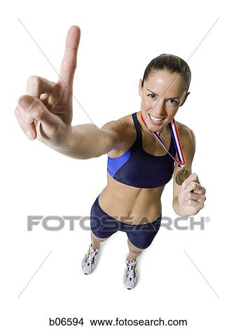 Woman athlete holding medal and making hand gesture View Large Photo Image Picture - Woman athlete holding medal and making hand gesture. Fotosearch