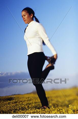 Stock Photo - Woman balancing on one leg in field. Fotosearch
