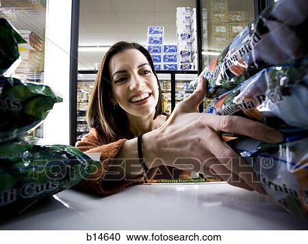 Woman buying bags of lettuce at grocery store smiling View Large Photo Image Stock Image - Woman buying bags of lettuce at grocery store smiling. Fotosearch