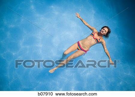 Woman floating in swimming pool View Large Photo Image Stock Image - Woman floating in swimming pool. Fotosearch