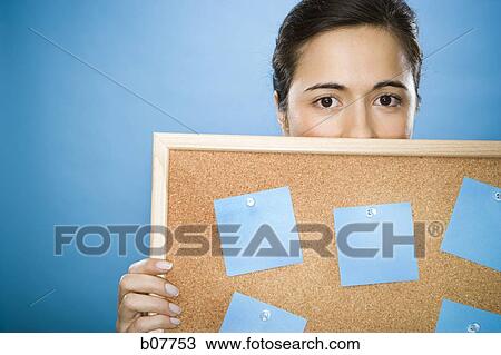 Stock Image - Woman holding a bulletin board with blank sticky notes. Fotosearch