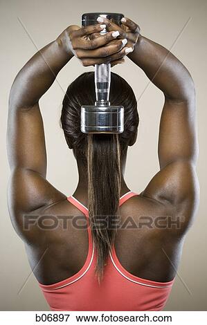 Woman holding dumbell behind head View Large Photo Image Stock Photo - Woman holding dumbell behind head. Fotosearch